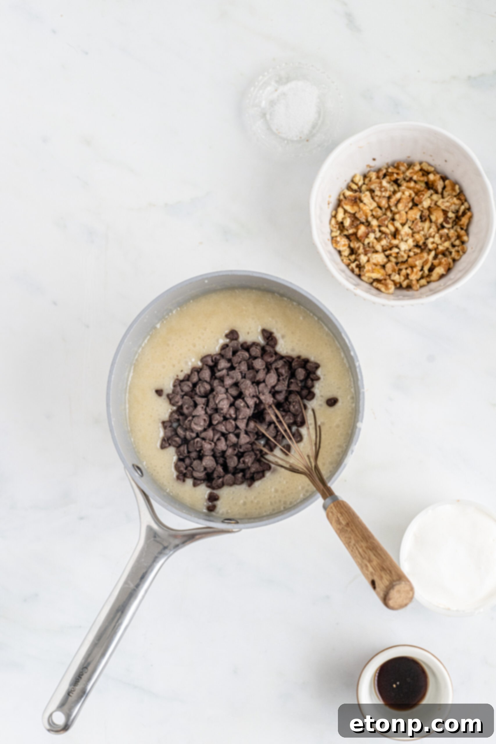 Overhead shot of ingredients melted in saucepan with chocolate chips poured on top. 