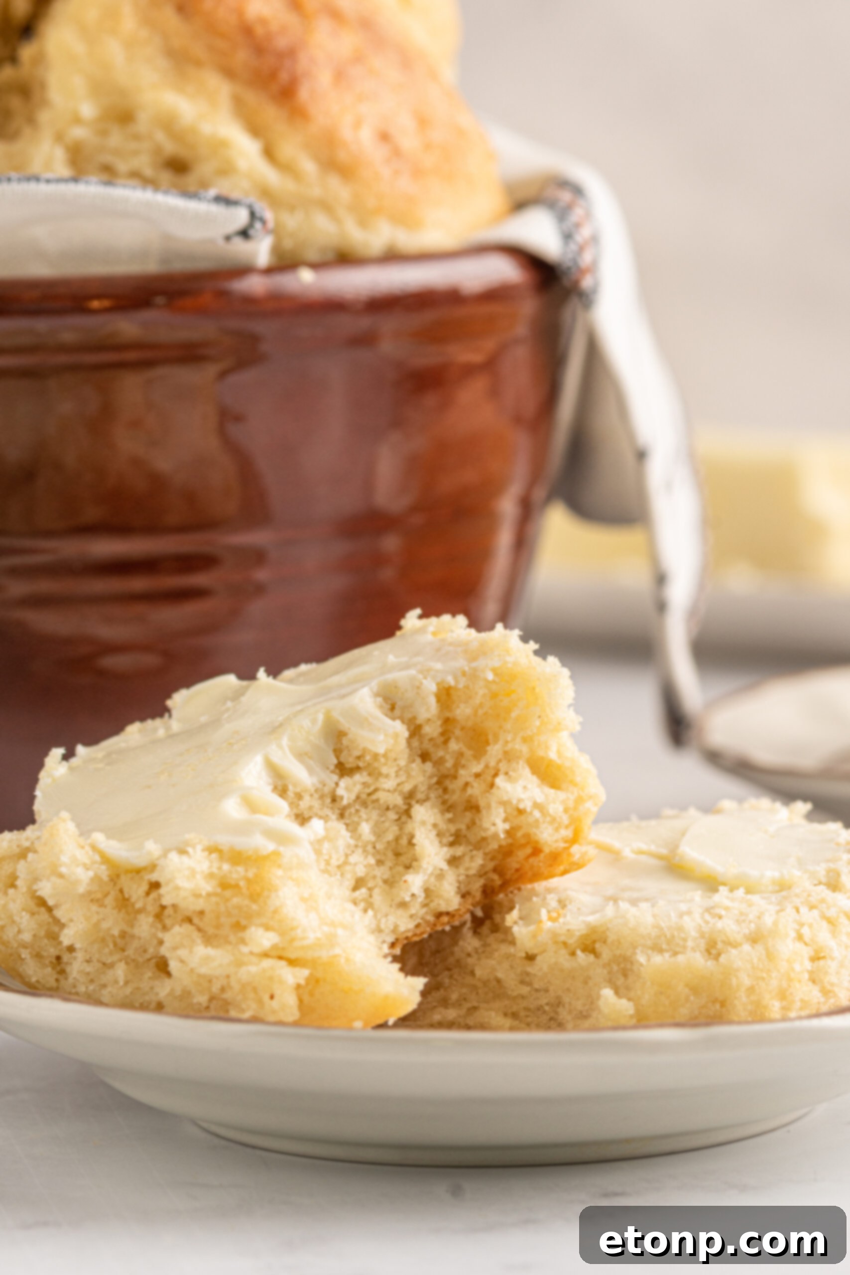 A biscuit cut in half showing the fluffy center topped with butter. 
