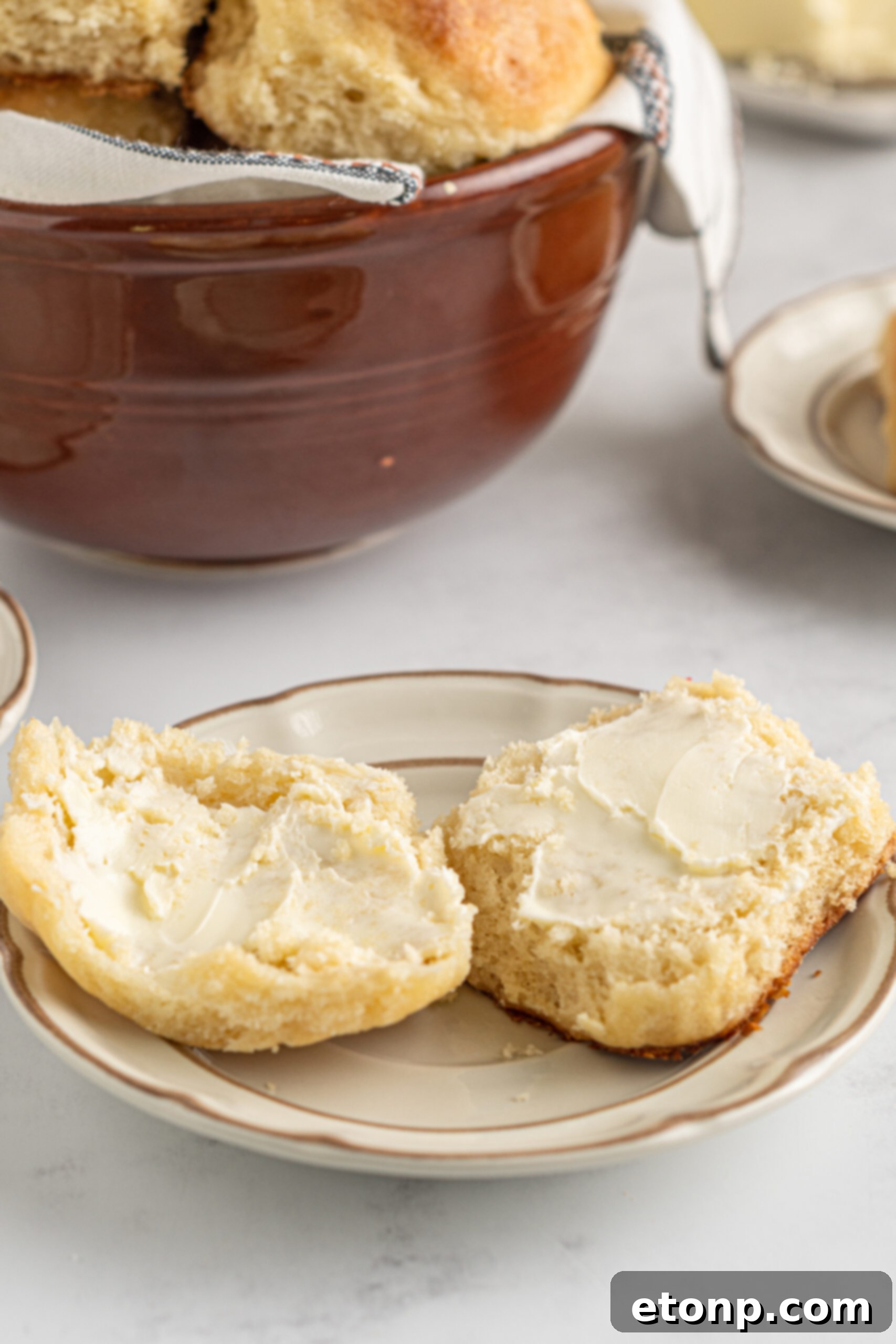 A biscuit cut in half showing the fluffy center topped with butter. 