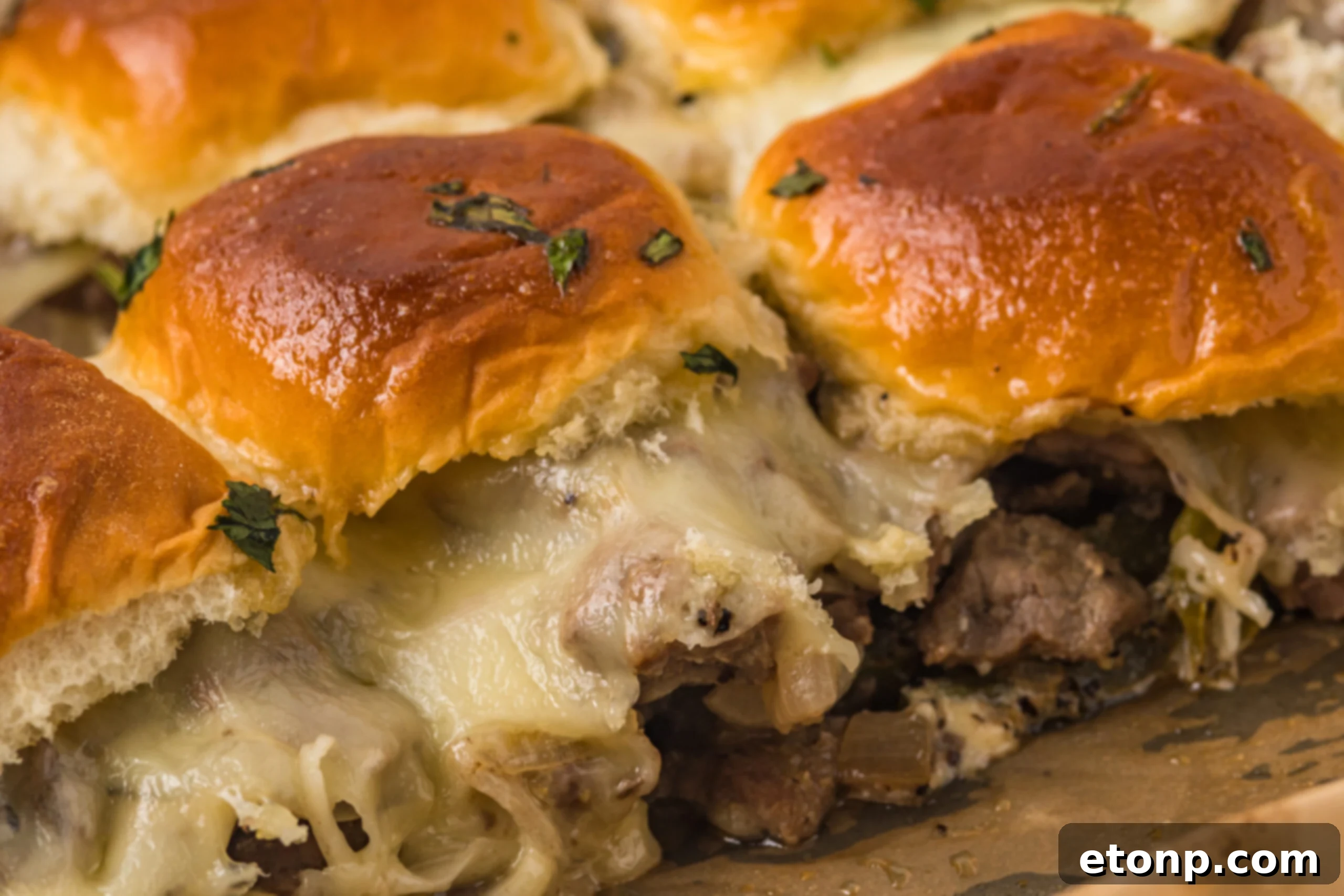 Philly Cheesesteak Sliders on a baking sheet up close to see melty cheese and texture.