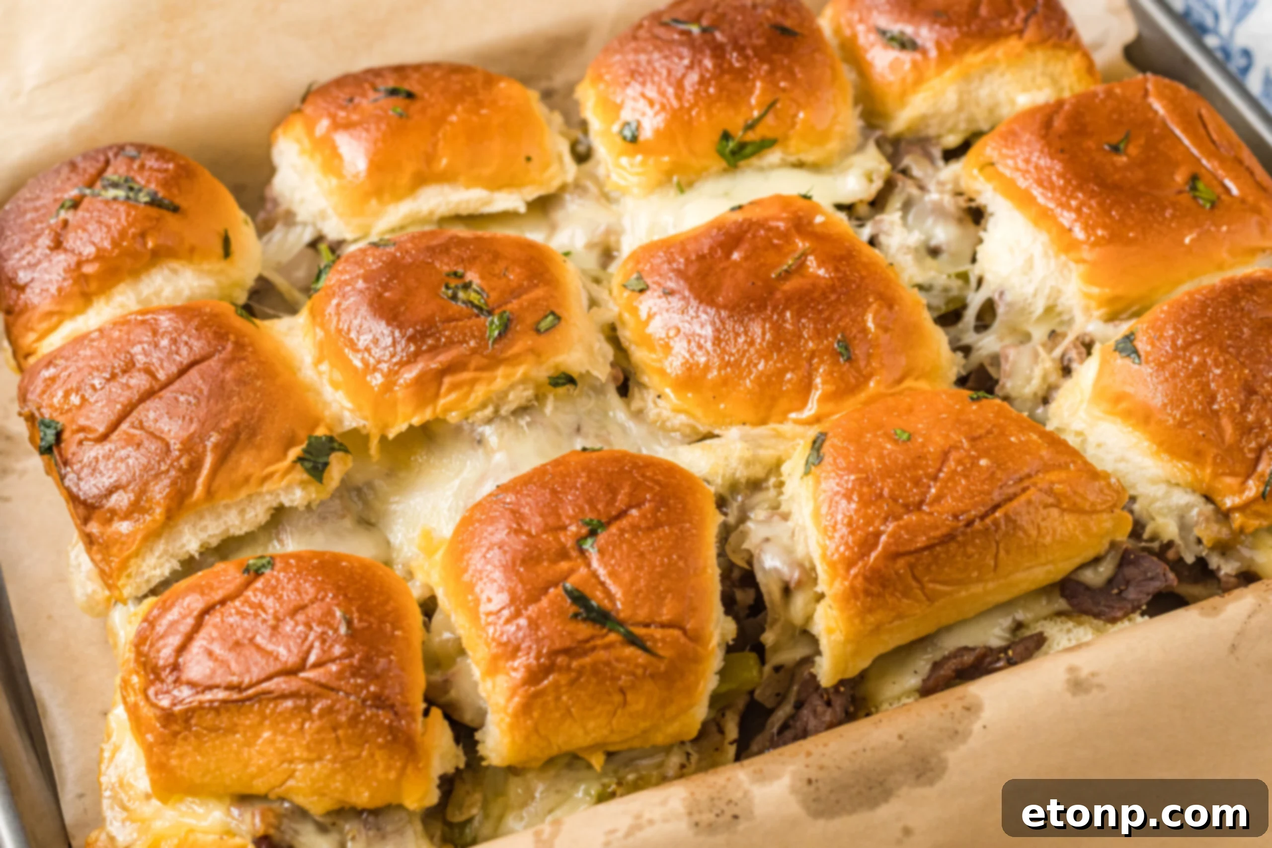 Philly Cheesesteak Sliders on a baking sheet, oozing with melty cheese!