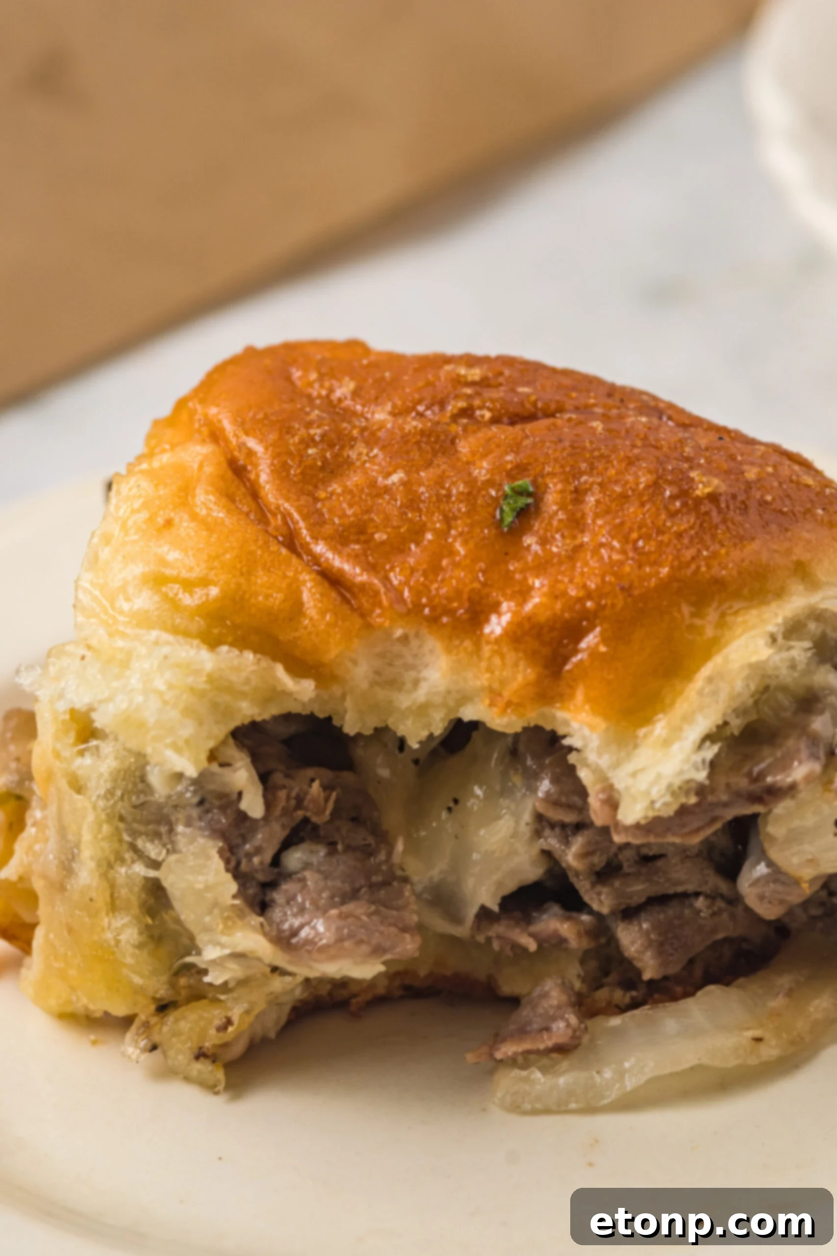 One slider on a white plate with a bite removed showing the inside. 