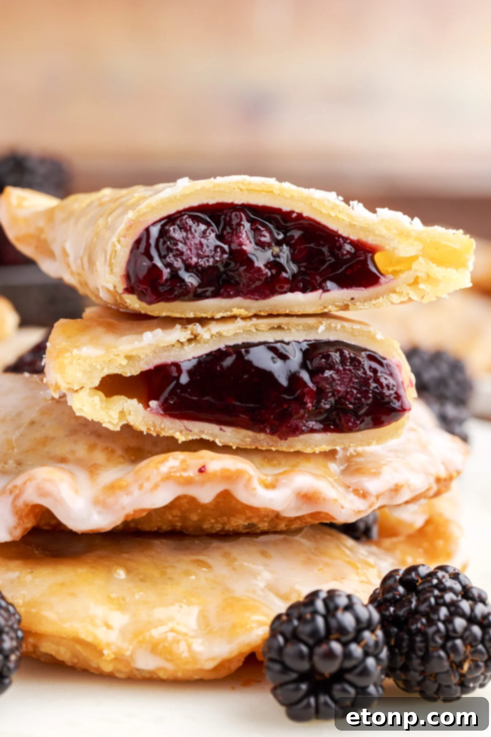 Rustic Blackberry Turnovers 2 A blackberry hand pie cut in half and stacked on top of two other pies showing the berry filling.