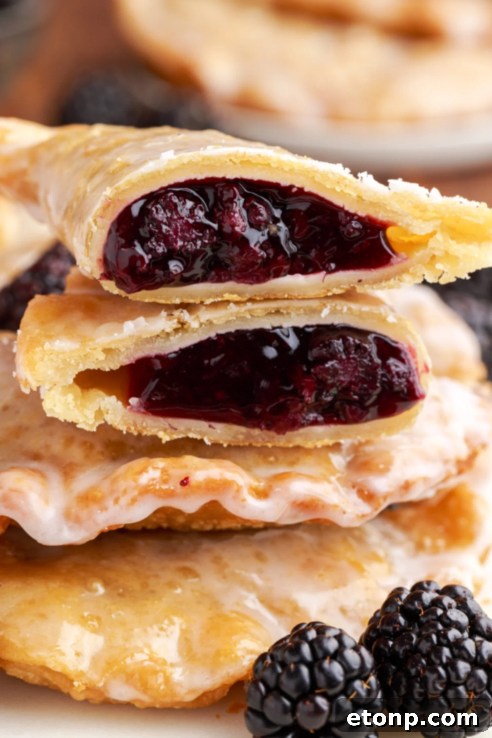 Rustic Blackberry Turnovers 13 A blackberry hand pie cut in half and stacked on top of two other pies showing the berry filling.