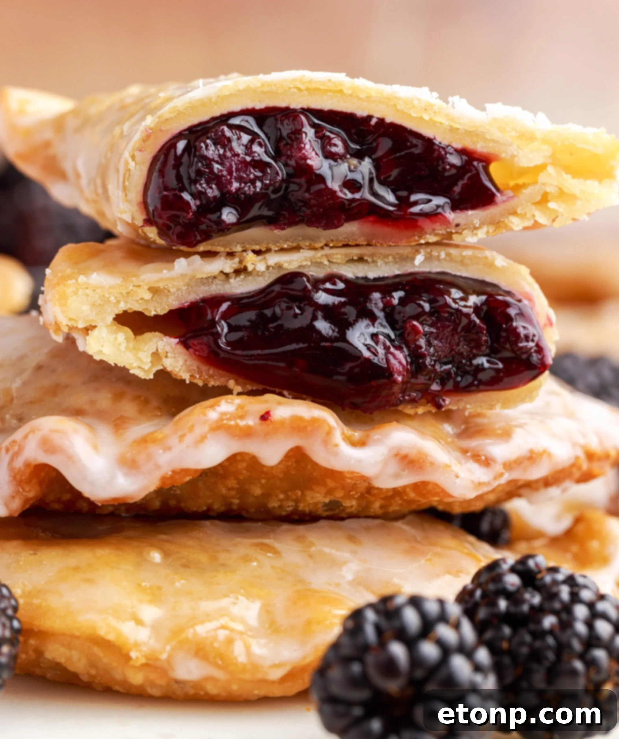 Rustic Blackberry Turnovers 14 A blackberry hand pie cut in half and stacked on top of two other pies showing the berry filling.
