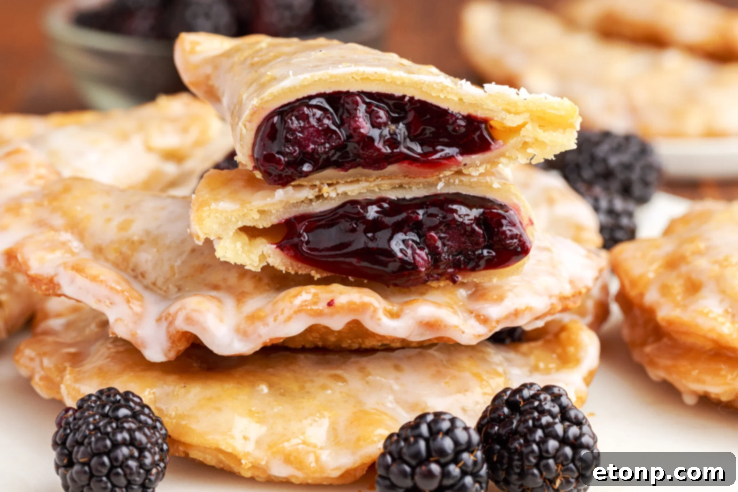 Rustic Blackberry Turnovers 16 A blackberry hand pie cut in half and stacked on top of two other pies showing the berry filling.