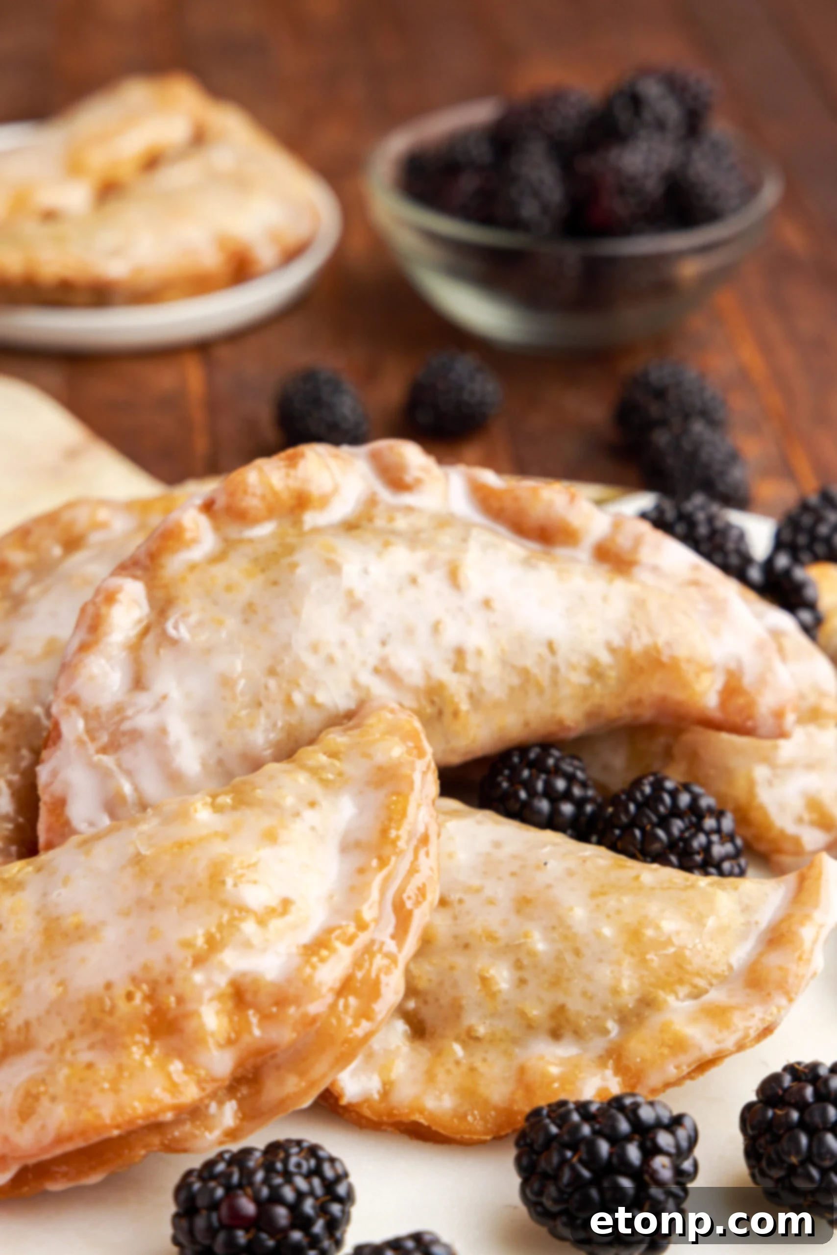 Rustic Blackberry Turnovers 3 Hand pies stacked on a marble serving tray with fresh blackberries.