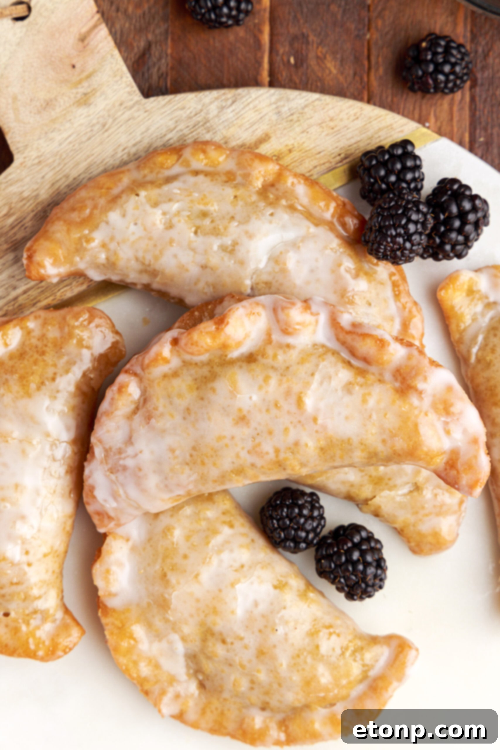 Rustic Blackberry Turnovers 4 Overhead shot of blackberry hand pies stacked on a marble serving tray with fresh blackberries.
