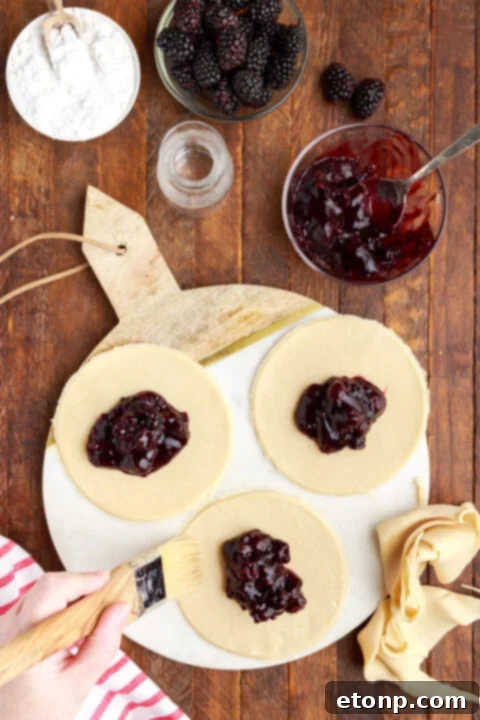 Rustic Blackberry Turnovers 8 three circle of pie dough on a marble serving tray with blackberry jam in the center of each circle.