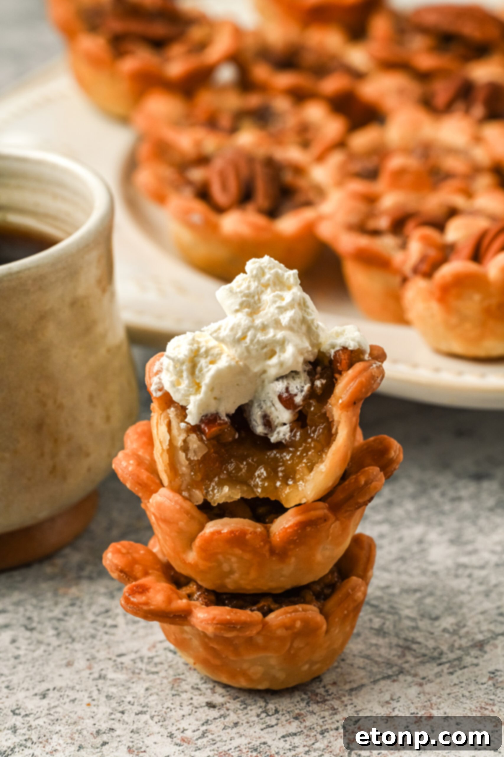 Three mini pies stacked on top of each other with a dollop of whipped cream. A small bite has been taken from the top pie, revealing its rich, gooey filling.