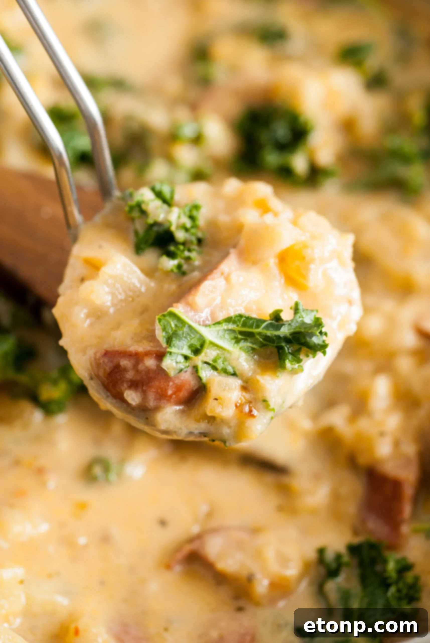 A ladle full of Kielbasa Potato Soup, showing creamy broth, chunks of potato, and slices of kielbasa. 