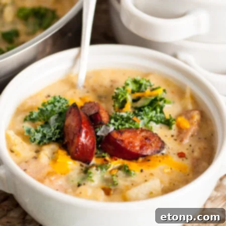 A bowl of Kielbasa Potato Soup topped with fresh kale and cooked kielbasa.