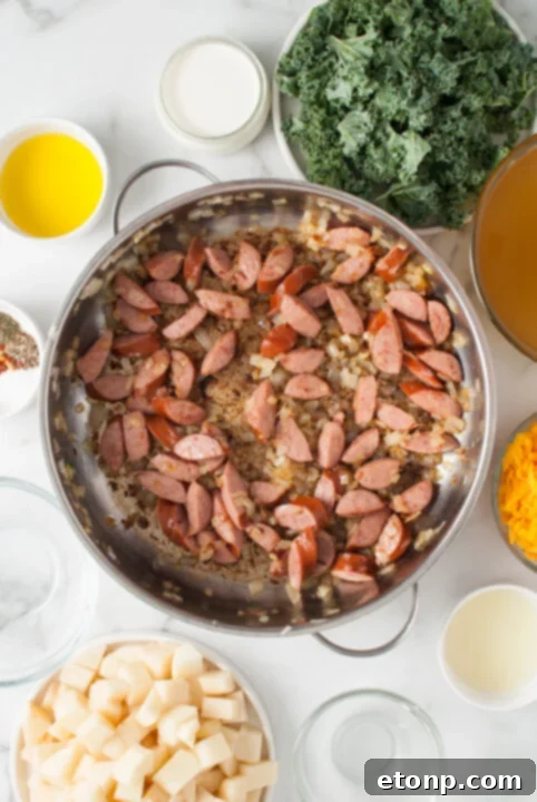 Close-up of golden brown kielbasa slices and sautéed onions in a pot.