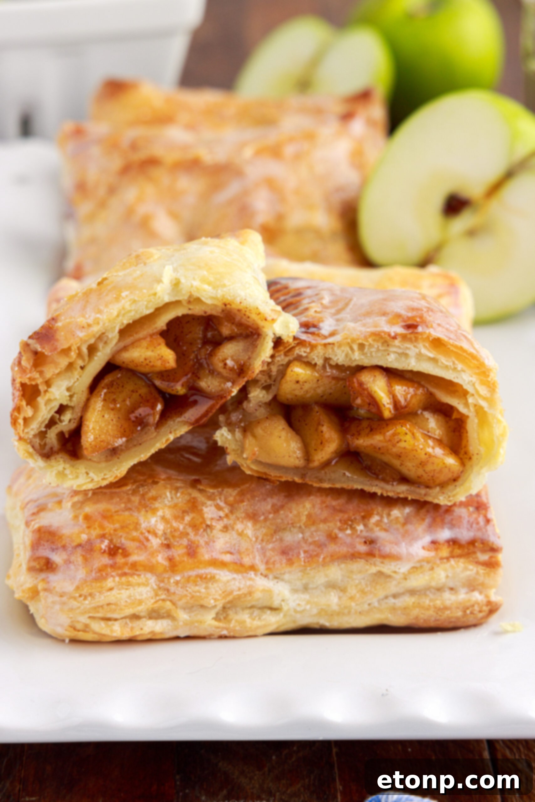A perfectly baked apple hand pie cut in half, revealing the warm, spiced apple filling nestled within the flaky golden crust.