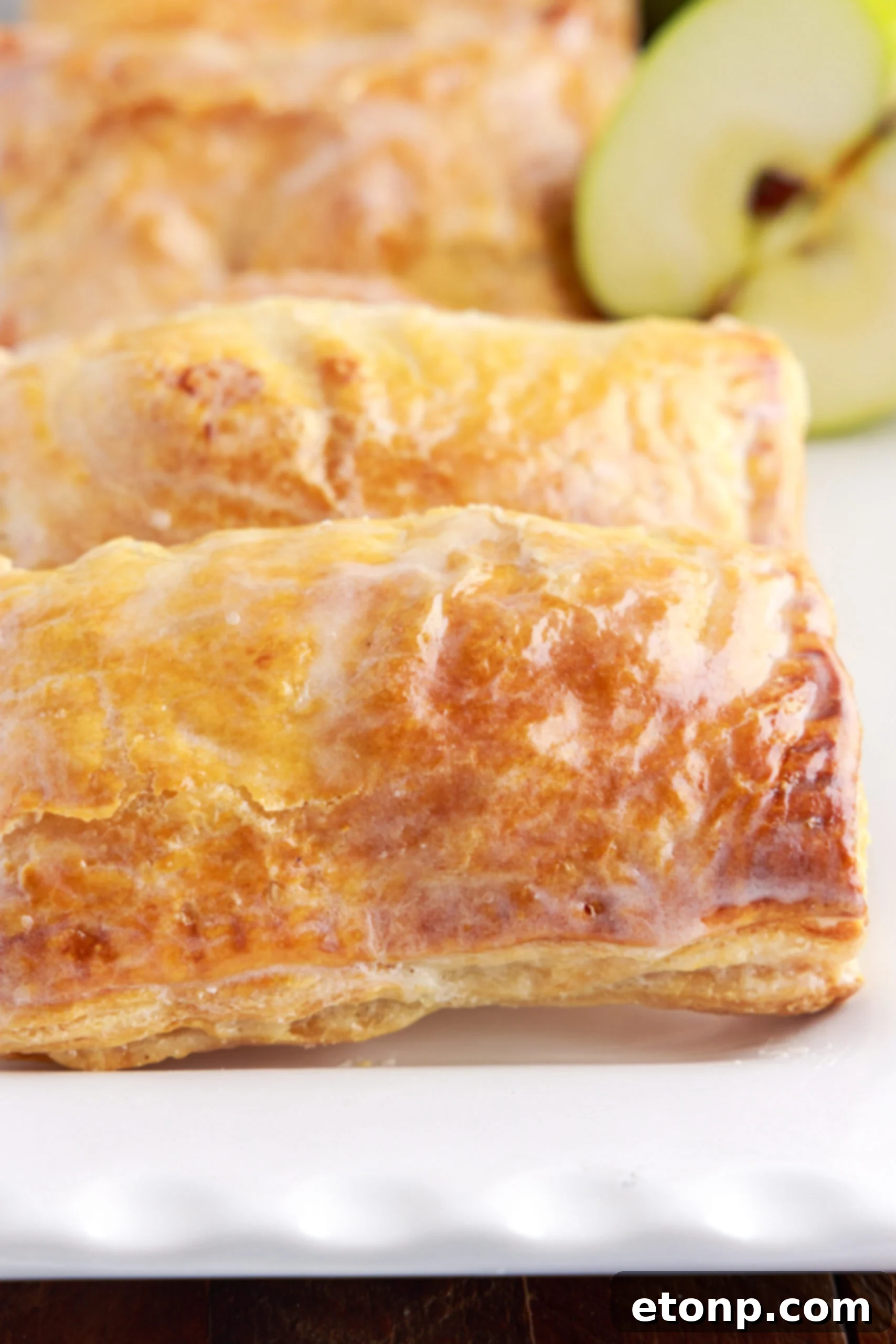 A close-up view of a baked apple hand pie with a delicate glaze, emphasizing the golden crust and enticing texture.