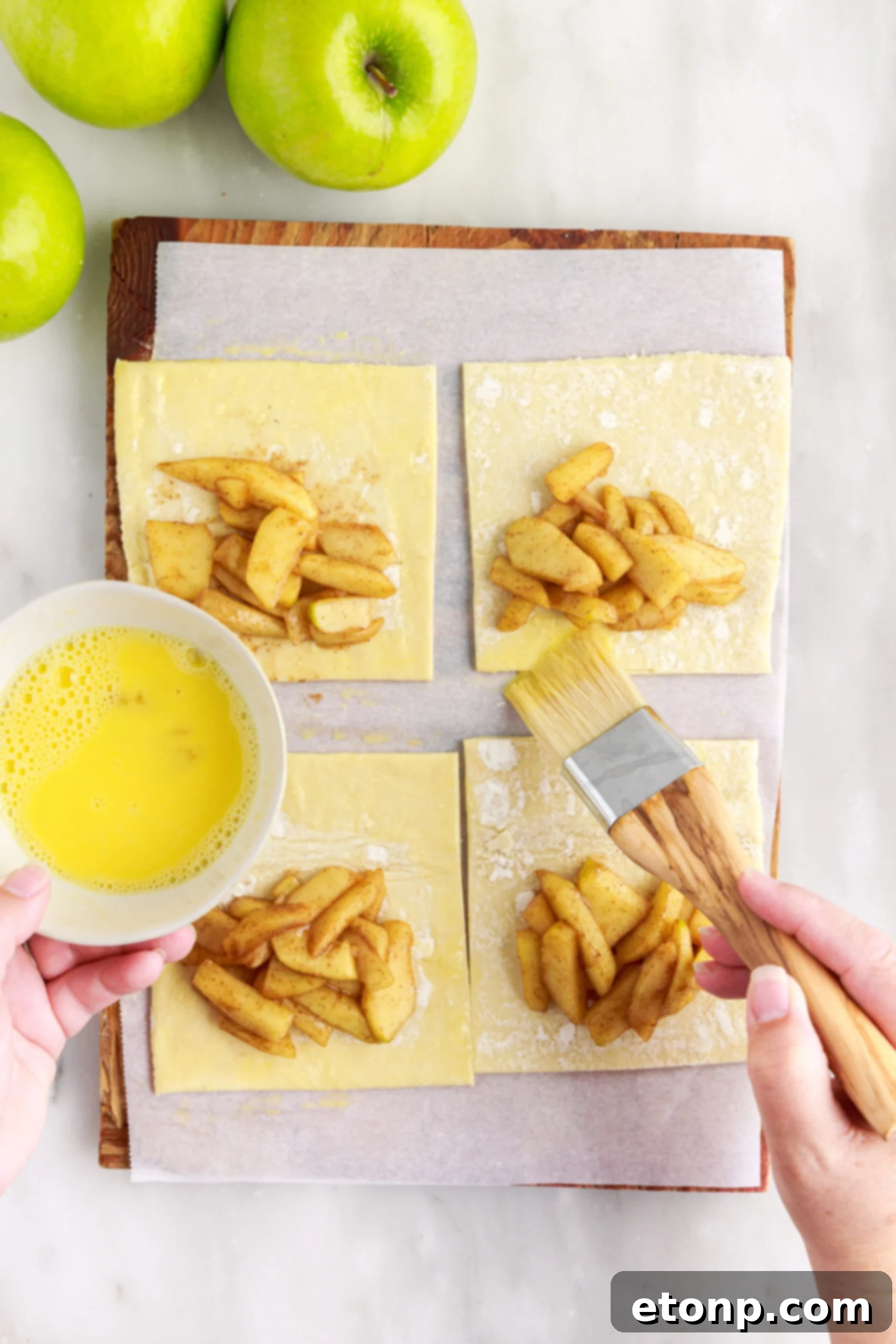 Apple filling being placed in the center of a puff pastry square.