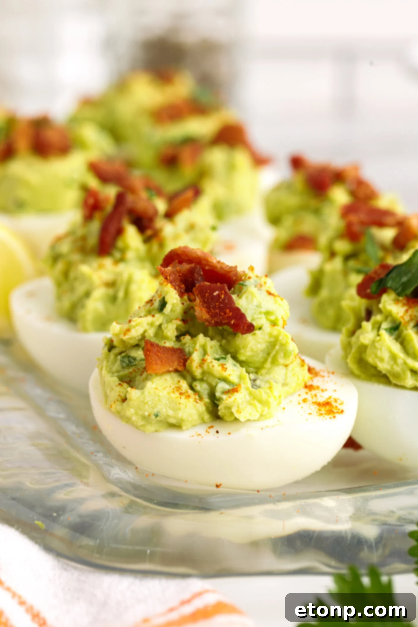 Side view of Avocado Deviled Eggs topped with chopped bacon. 