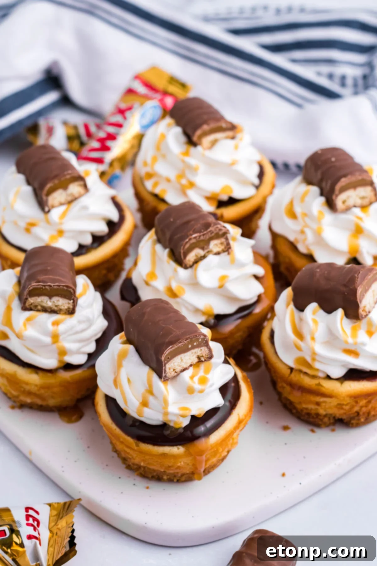 Decadent Mini Twix Cheesecakes 3 Overhead view of the mini Twix cheesecakes on a white marble serving board.