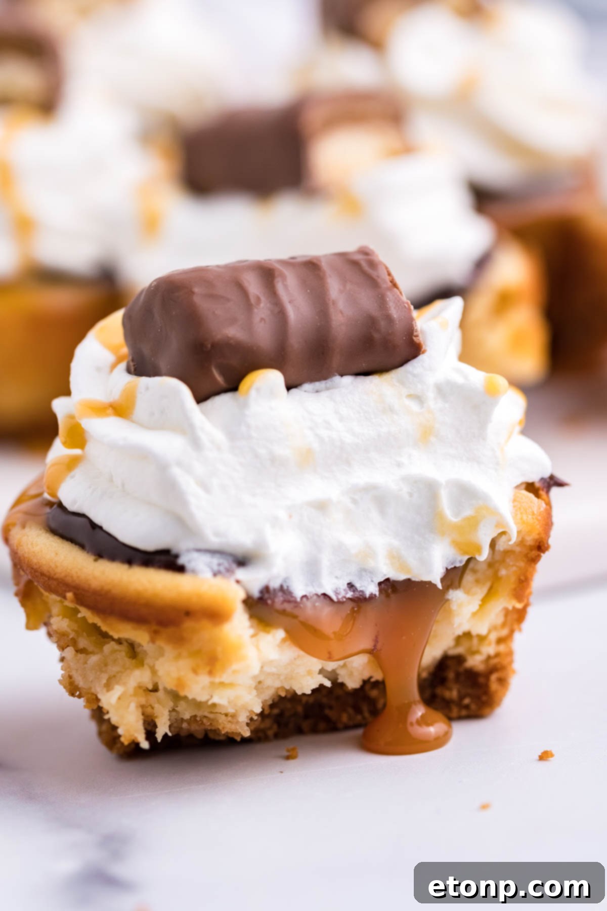 Decadent Mini Twix Cheesecakes 5 A mini cheesecake cut in half showing the caramel filling.