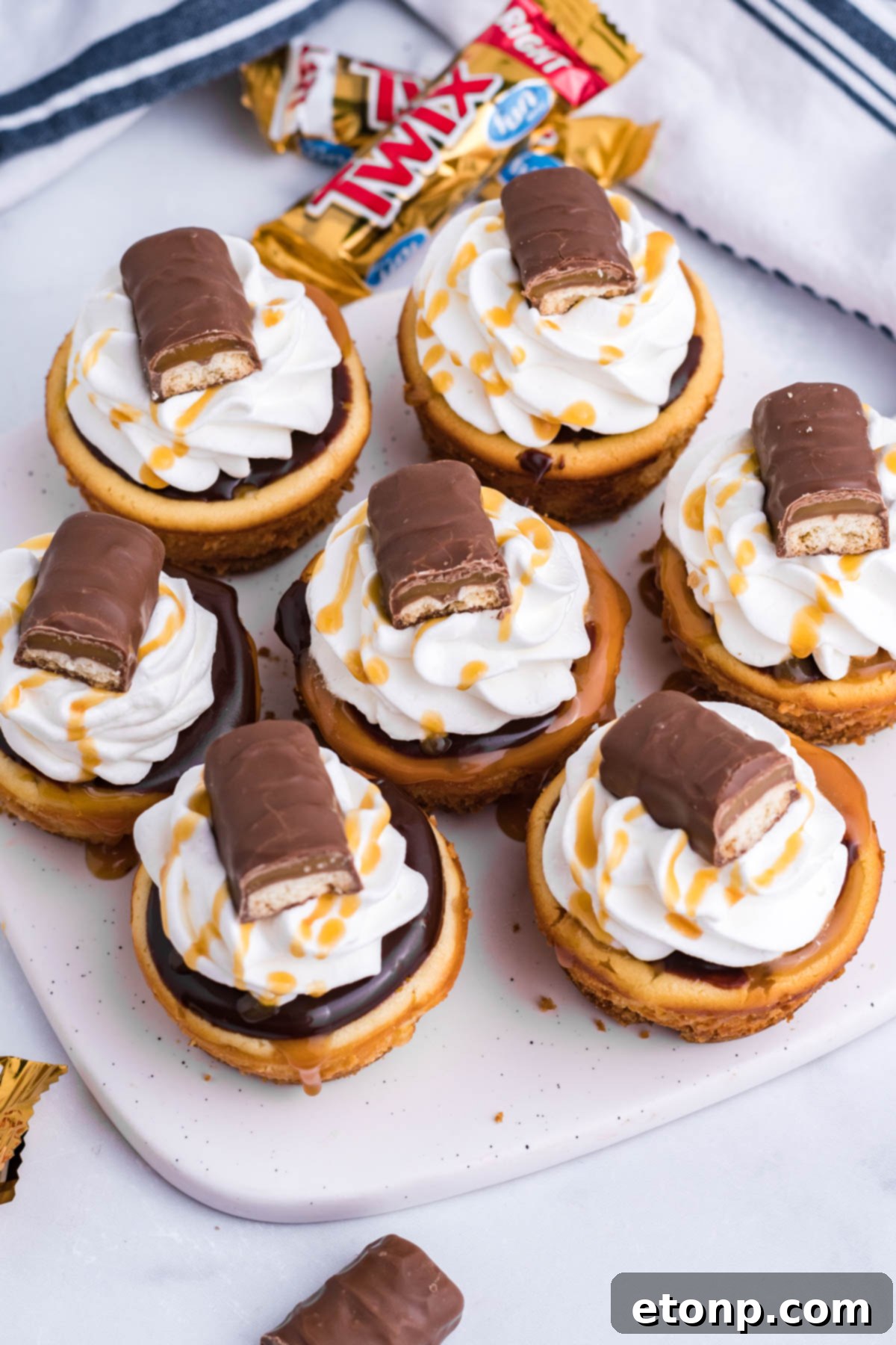 Decadent Mini Twix Cheesecakes 8 Overhead view of the mini Twix cheesecakes on a white marble serving board.