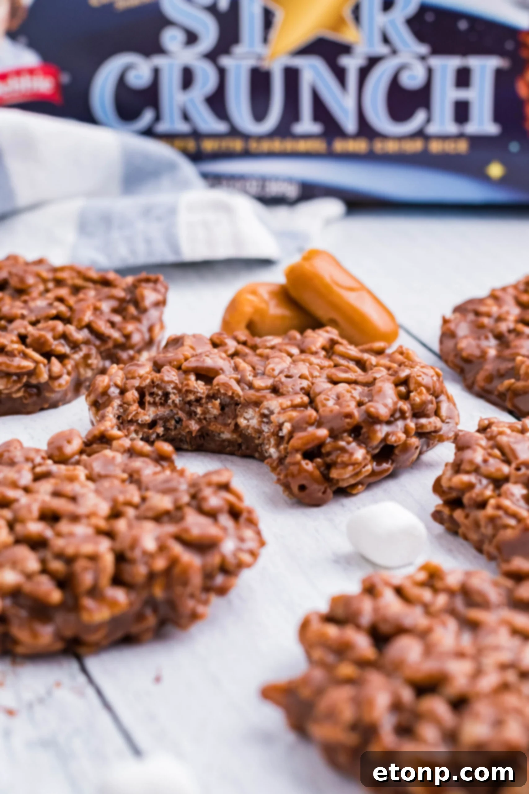 Star Crunch cookies on a white wooden surface with a bite removed showing the inside of the cookie. 