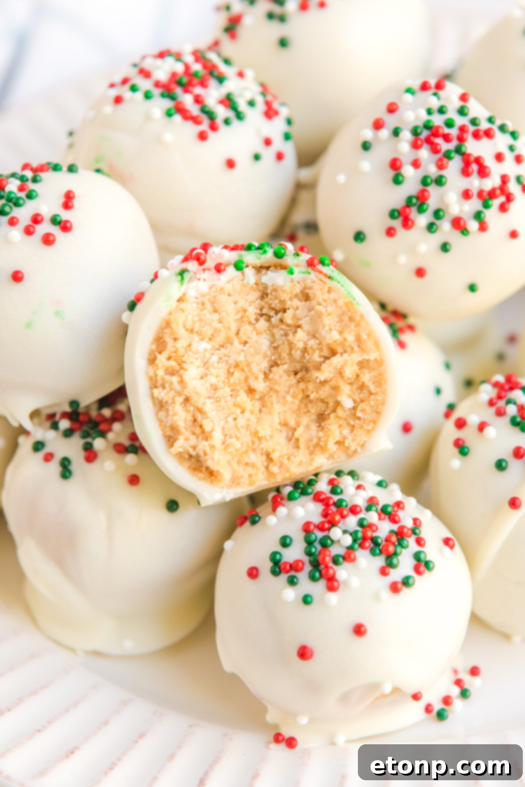 Irresistible White Chocolate Peanut Butter Snowballs 2 A White Chocolate Peanut Butter Snowball with a bite removed showing the inside, highlighting its creamy texture.