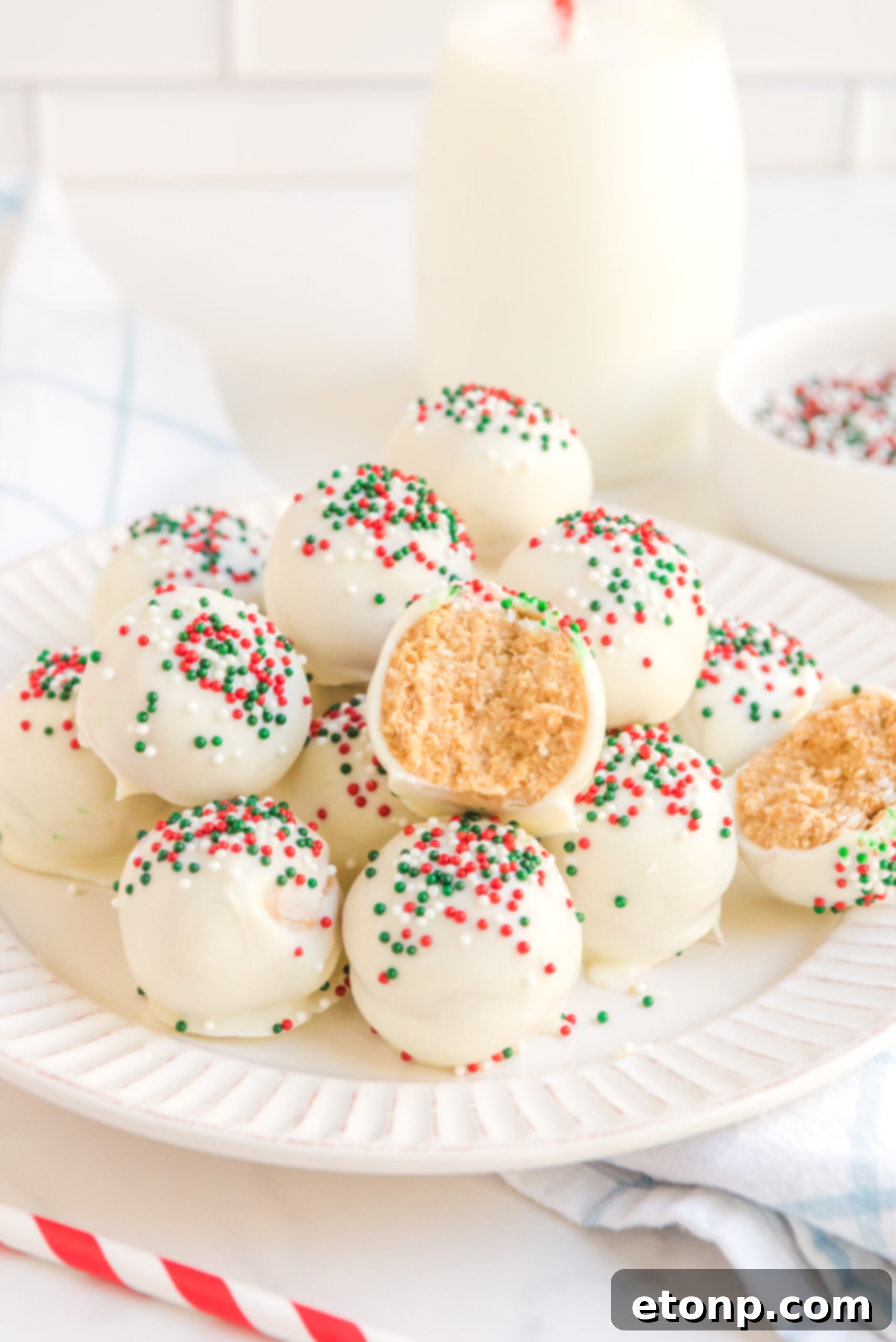 Irresistible White Chocolate Peanut Butter Snowballs 7 A charming stack of White Chocolate Peanut Butter Truffles on a white plate, generously adorned with festive red, white, and green sprinkles, ready to be enjoyed.