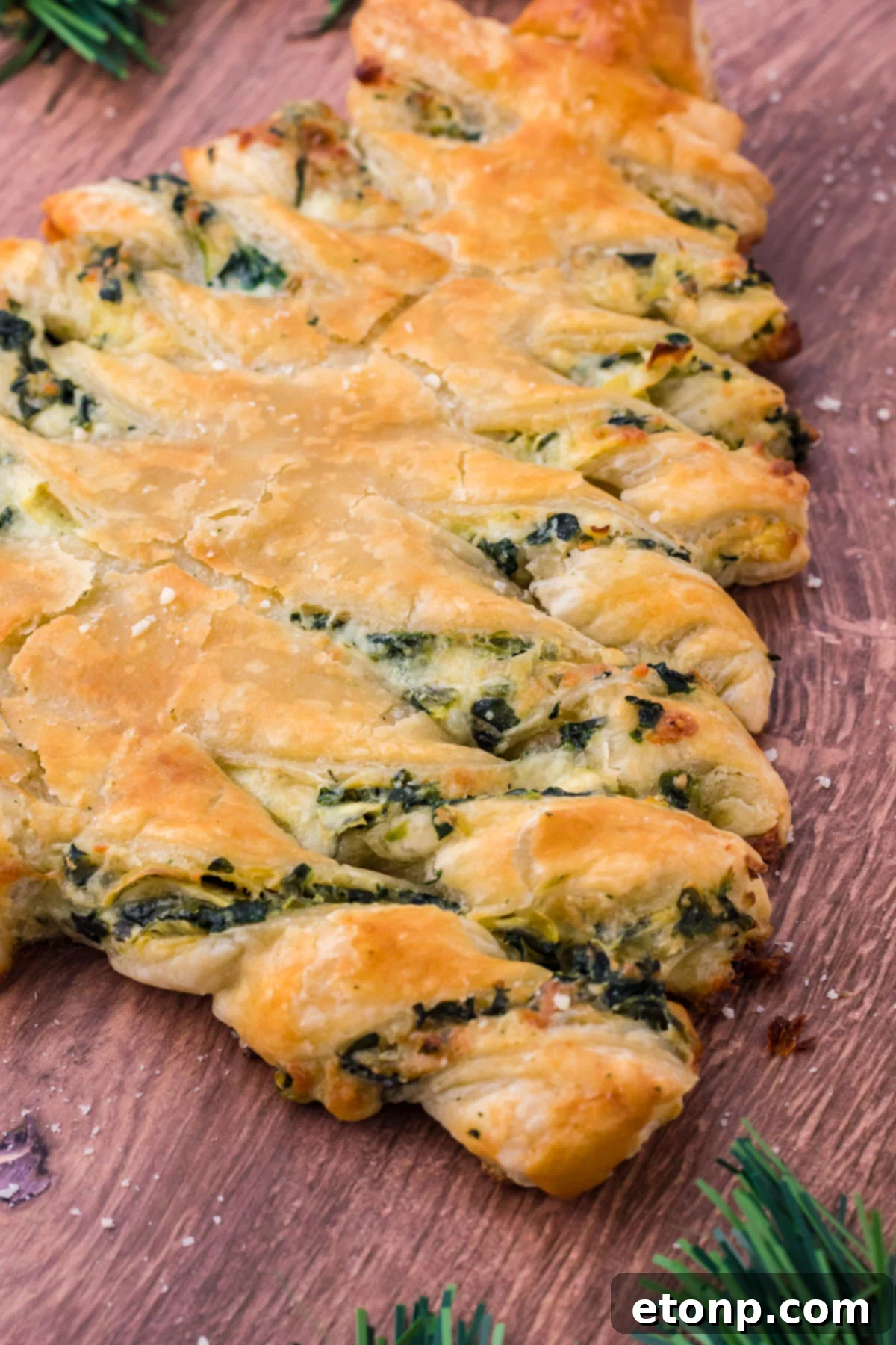 Side view of spinach dip pull apart Christmas tree bread on a dark wood background. 