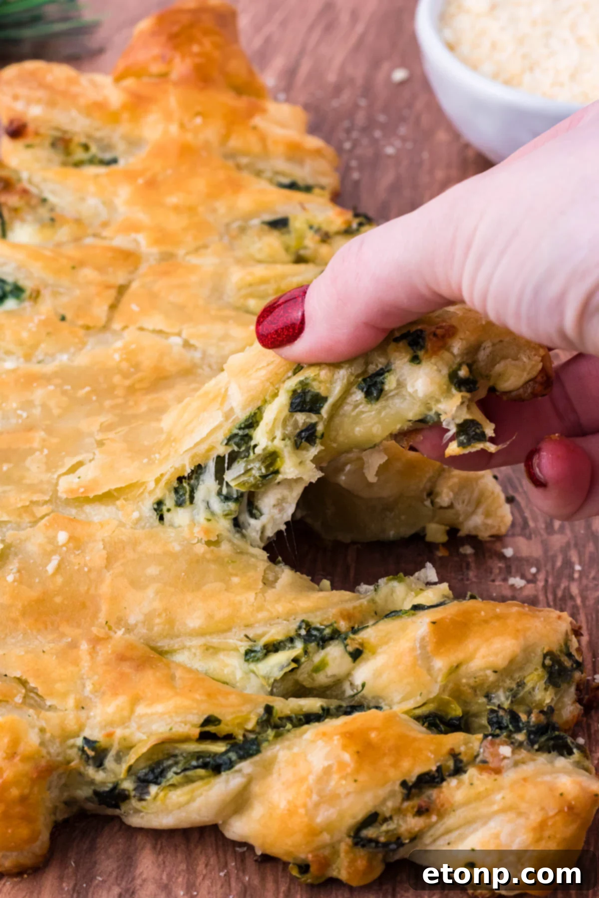Photo of  a piece of pull apart bread being removed showing the cheesy inside. 