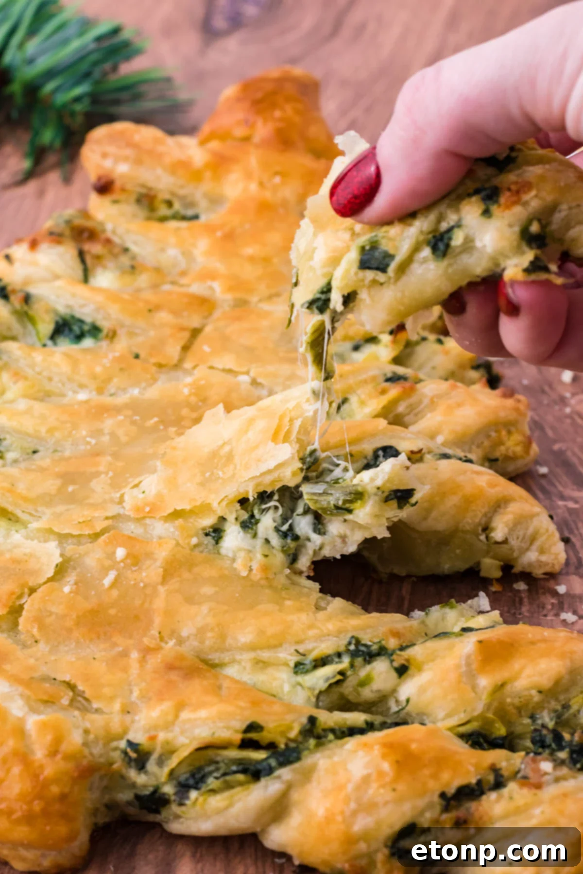 Photo of  a piece of pull apart bread being removed showing the cheesy inside. 