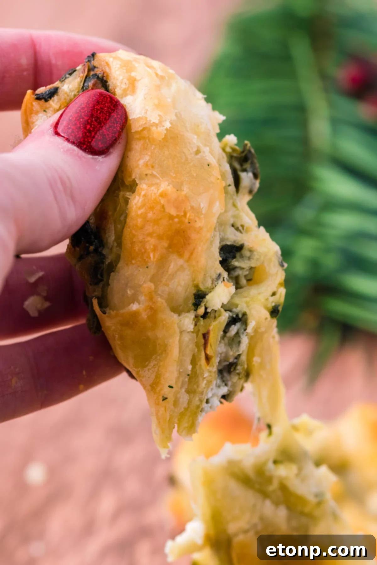 A piece of spinach dip pull apart bread being held up showing the flakey outside layer. 