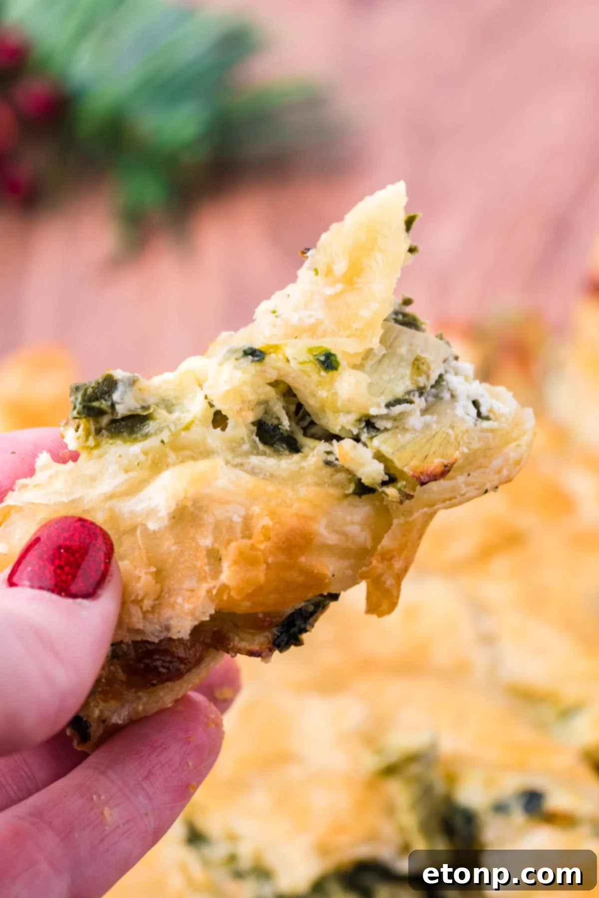 A piece of spinach dip pull apart bread being held up showing the flakey outside layer. 