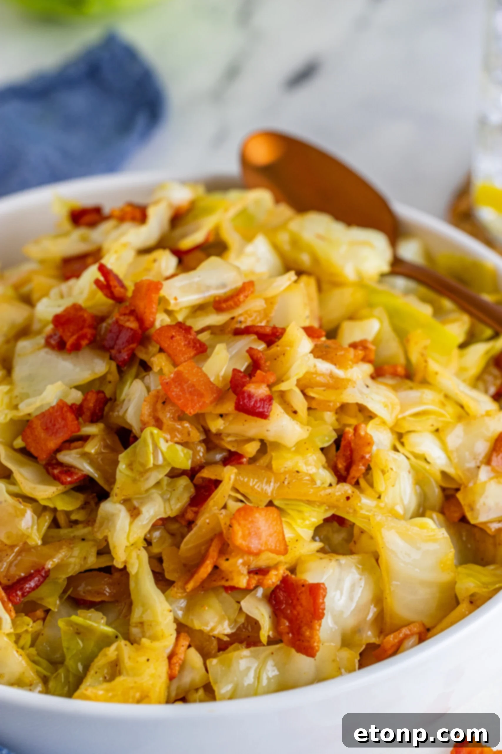Fried Cabbage in a white bowl with a gold spoon. 