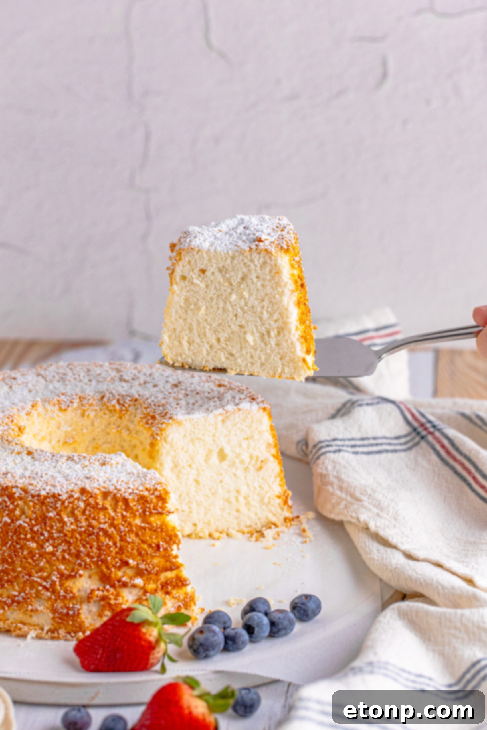 A piece of Angel Food Cake being removed with a silver spatula. 