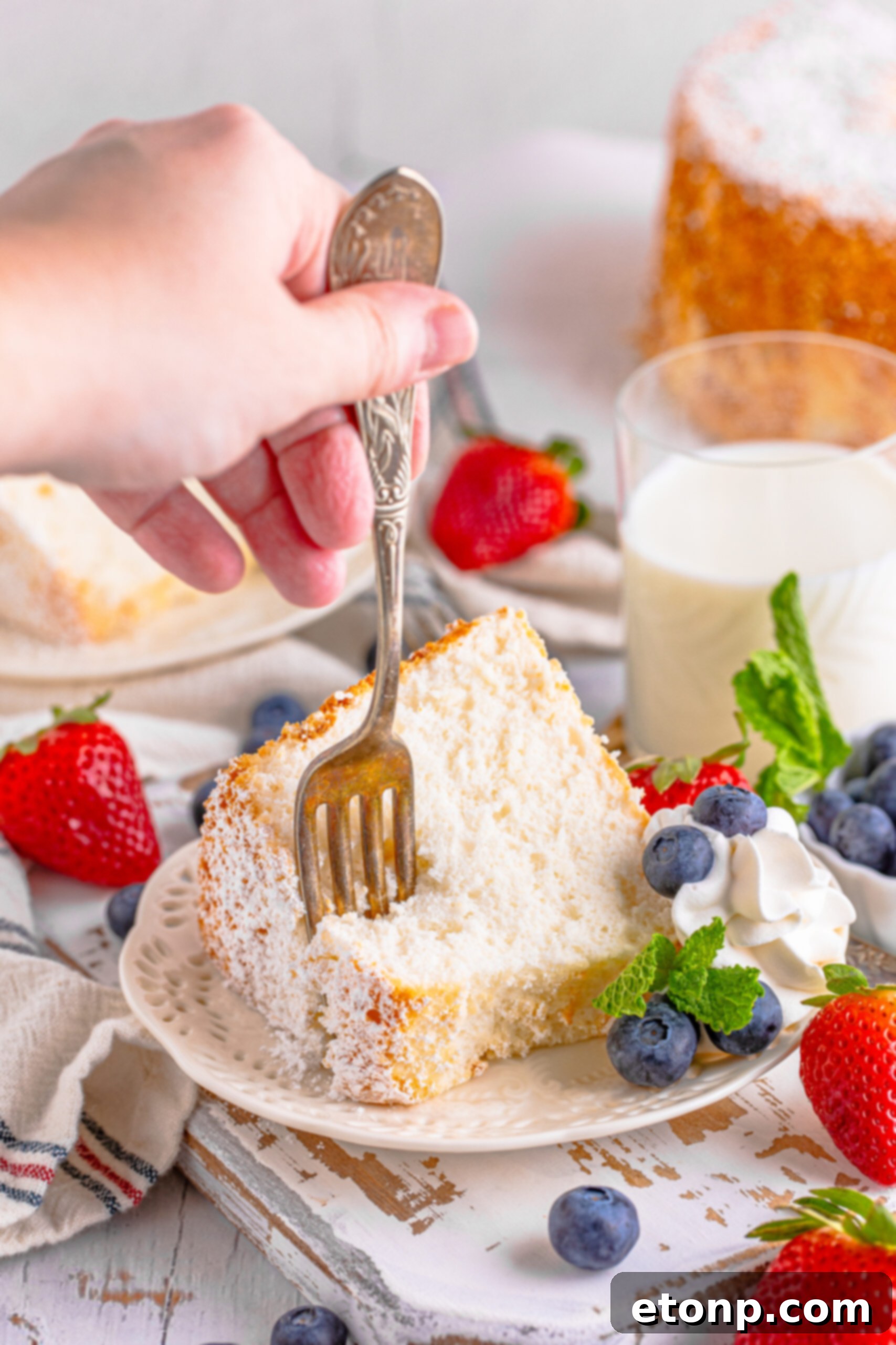 A fork removing a bite of cake from a white plate. 