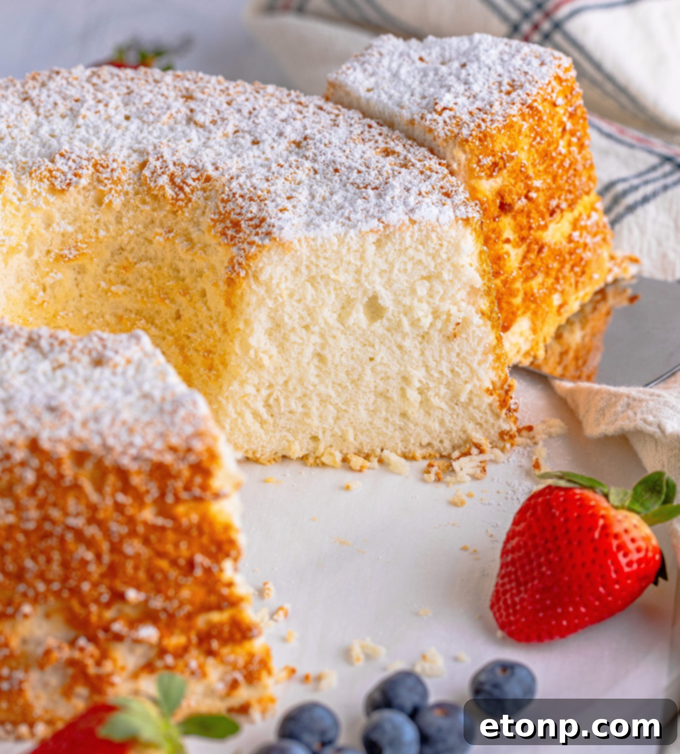 Angel Food Cake on a white serving platter with a slice removed 