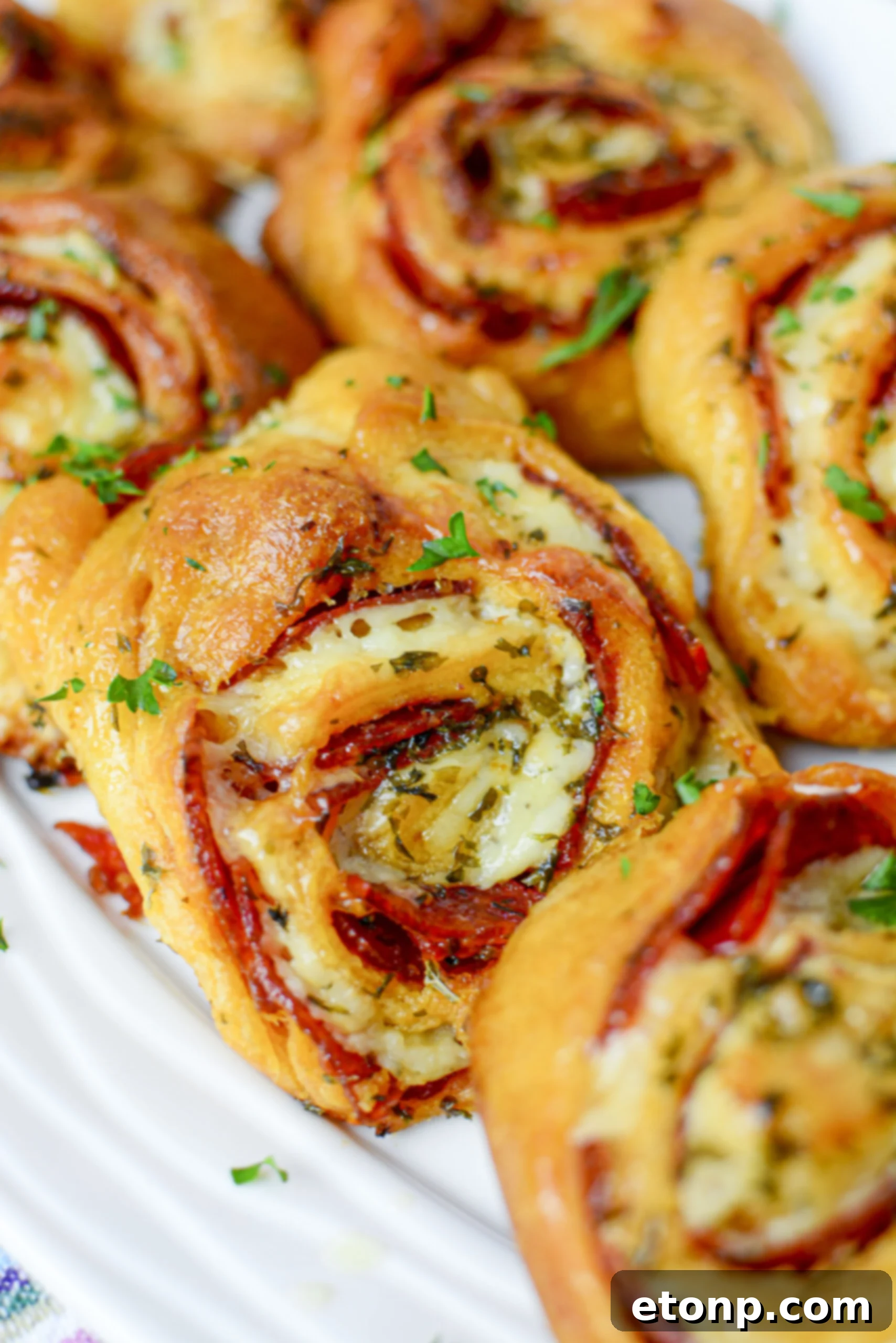Pizza Swirls 2 Freshly baked pizza pinwheels arranged neatly on a wooden cutting board, ready to be served.