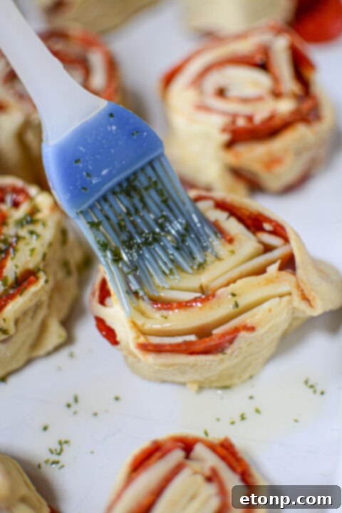 Pizza Swirls 11 A batch of baked pizza pinwheels in a baking dish, with steam gently rising, indicating freshness.