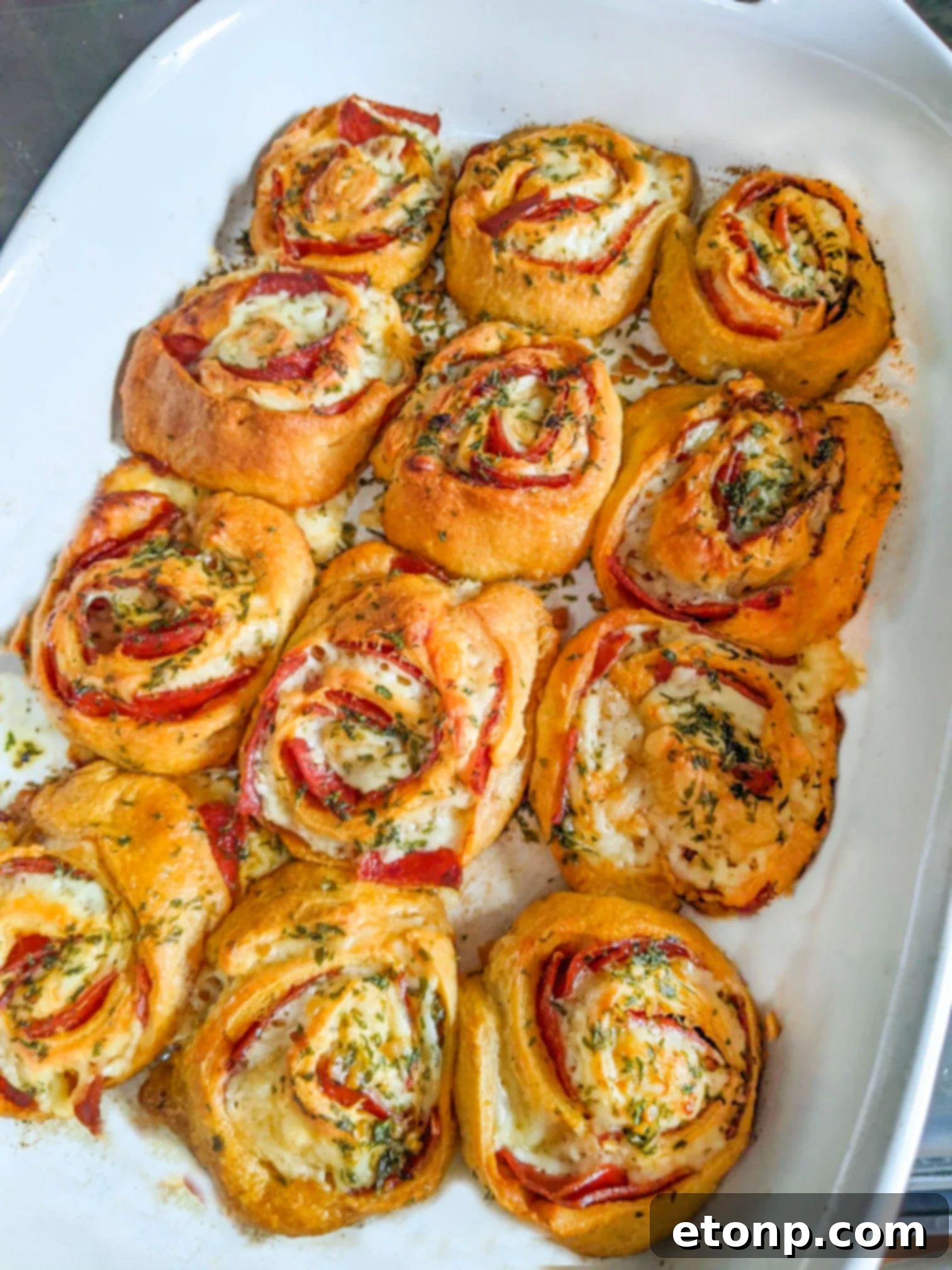 Pizza Swirls 13 A white baking pan filled with golden-brown pizza pinwheels, perfectly baked and ready to serve.