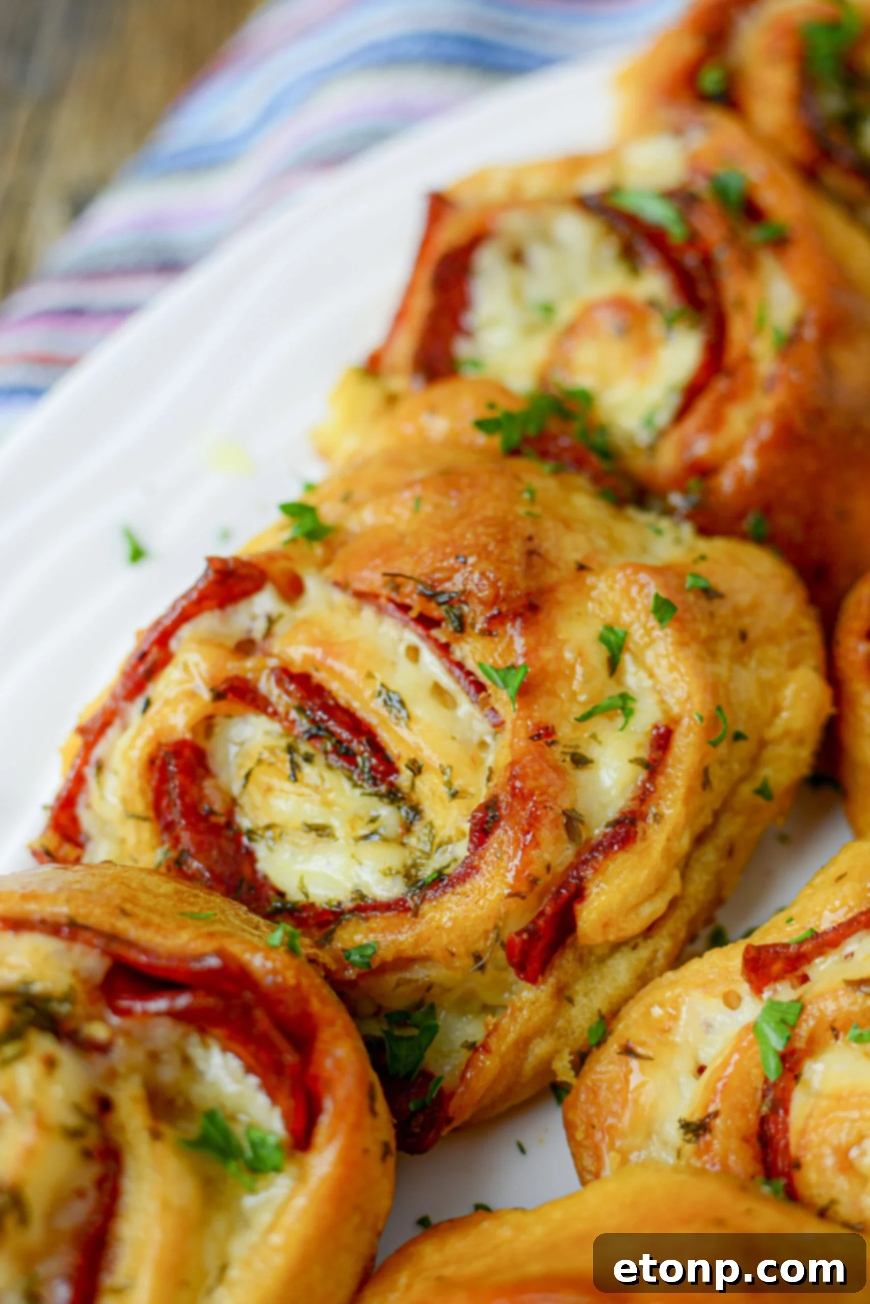 Pizza Swirls 14 Baked pizza pinwheels lined up on a crisp white plate, showcasing their inviting golden crust and cheesy filling.