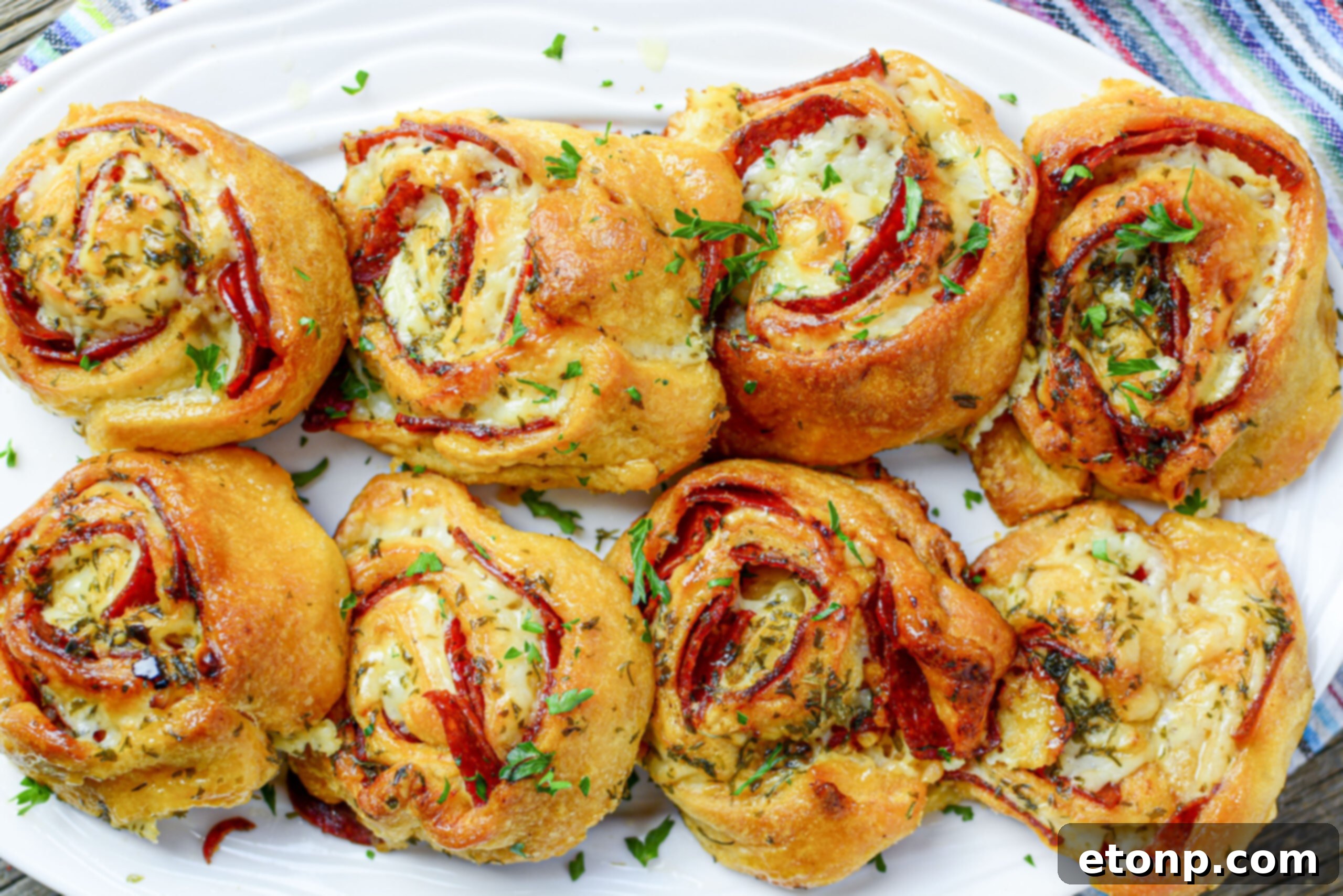 Pizza Swirls 15 A large white serving tray generously filled with dozens of freshly baked pizza pinwheels, ready for a party.