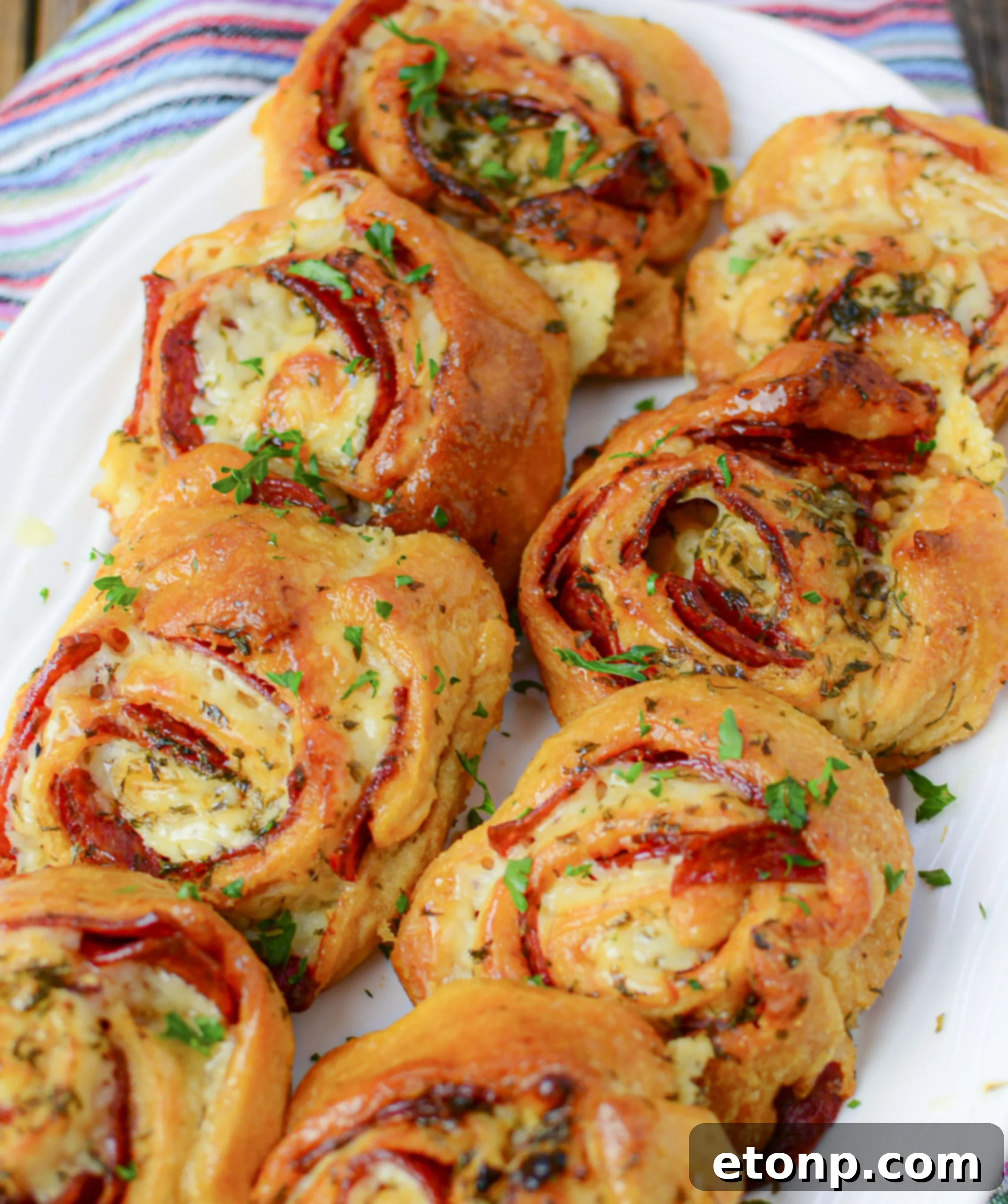 Pizza Swirls 16 Overhead shot of freshly baked pizza pinwheels arranged on a serving plate with a small bowl of marinara dipping sauce.