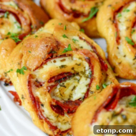 Pizza Swirls 17 Freshly baked pizza pinwheels arranged neatly on a wooden cutting board, ready to be served.