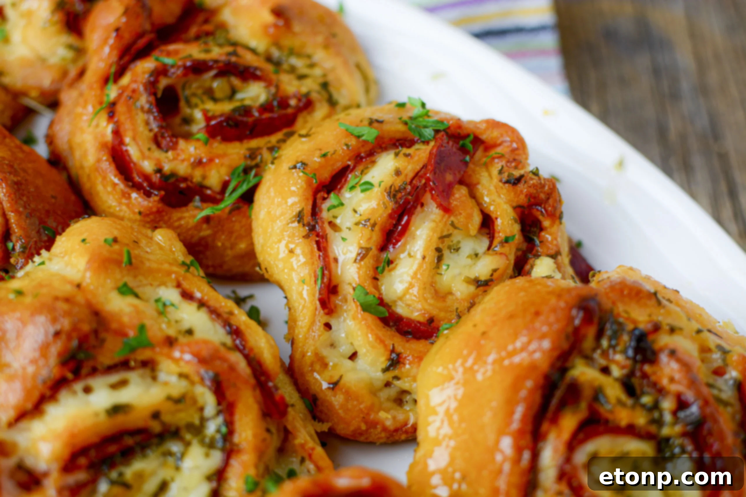Pizza Swirls 6 Stacked pizza pinwheels cooling in a metal rack after baking, showcasing their perfect golden crusts.