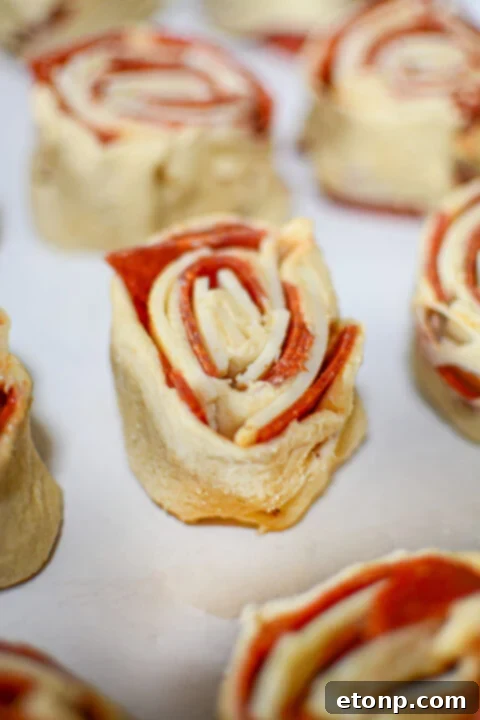 Pizza Swirls 10 Overhead view of several pizza pinwheels, showcasing their uniform size and appealing swirl.
