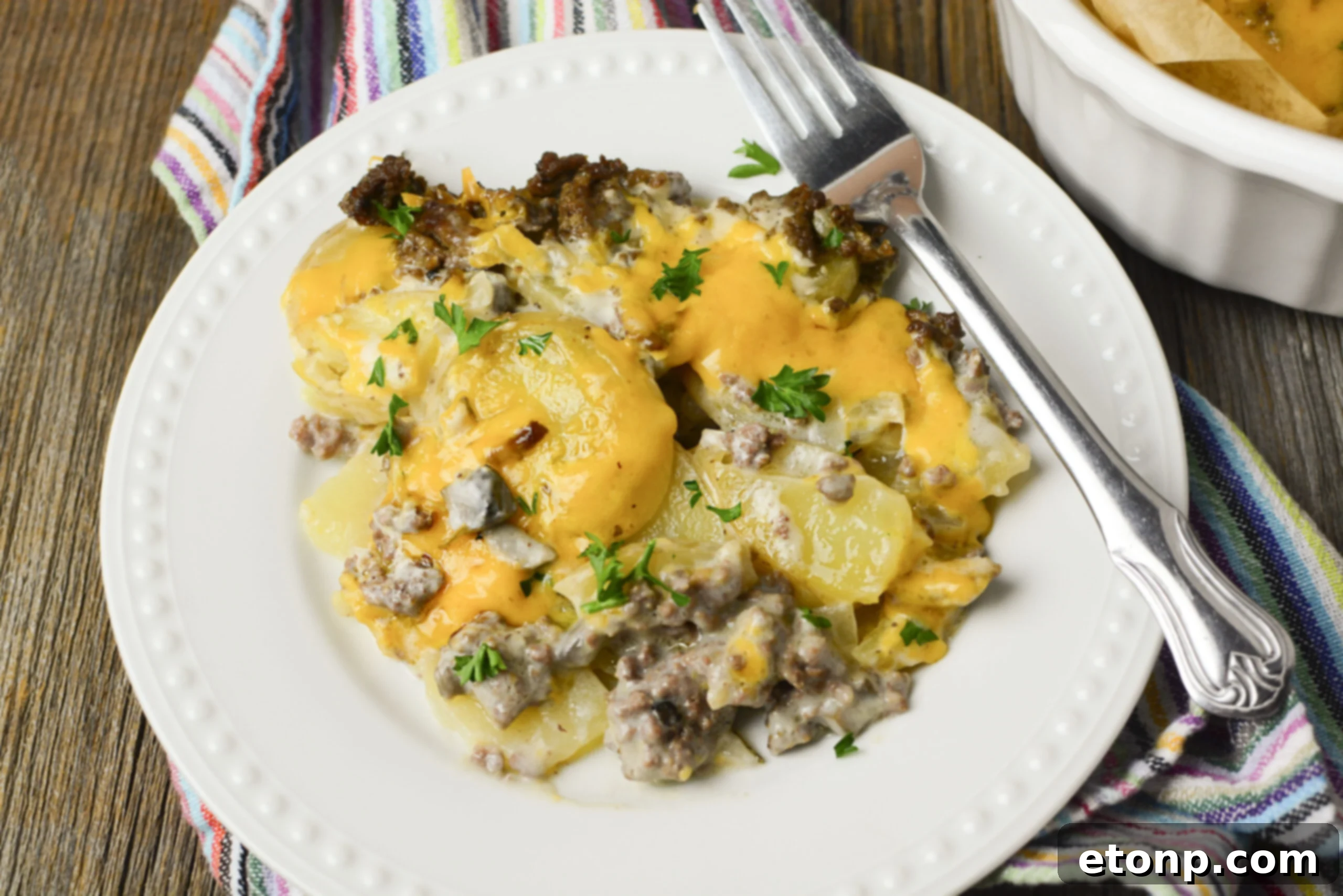 A delightful serving of Cheesy Ground Beef and Potato Casserole on a white plate, ready to be enjoyed.