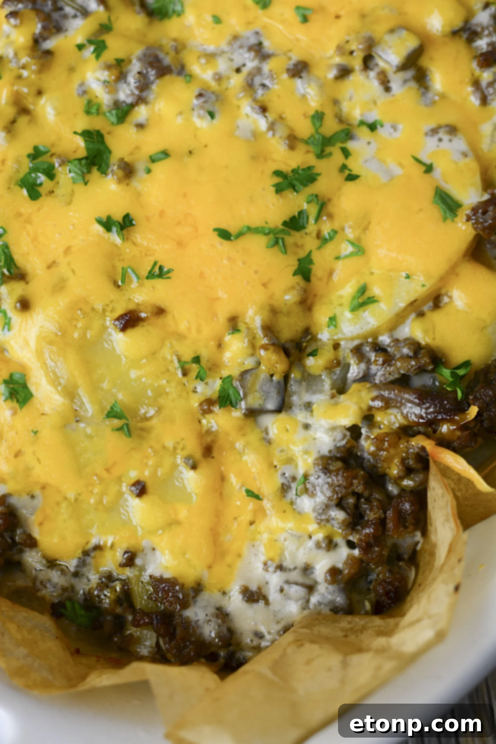 A close-up view of the bubbling, cheesy Ground Beef and Potato Casserole in a white baking dish, fresh from the oven.