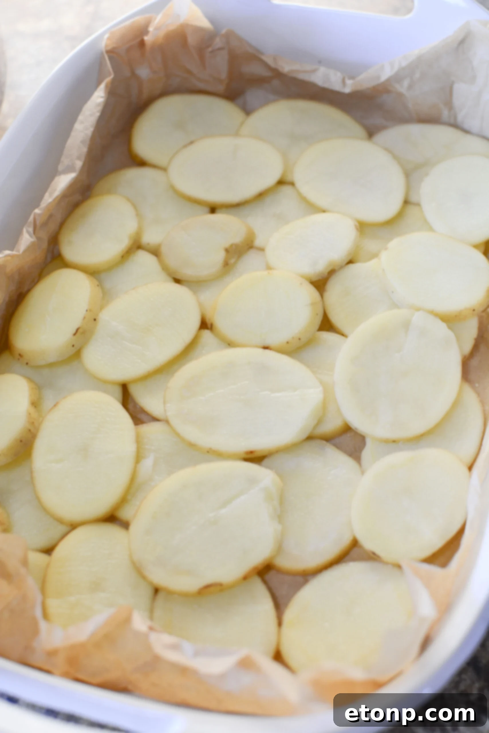 Adding sauce over layers of potatoes and ground beef in a casserole.