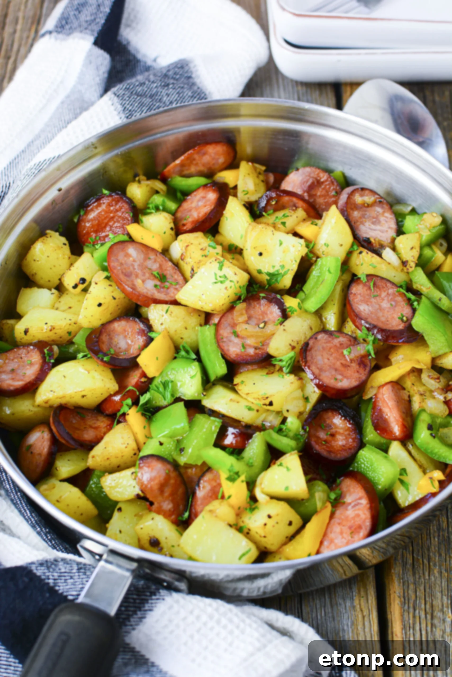 Overhead view of Sausage peppers and potatoes in a silver skillet. 
