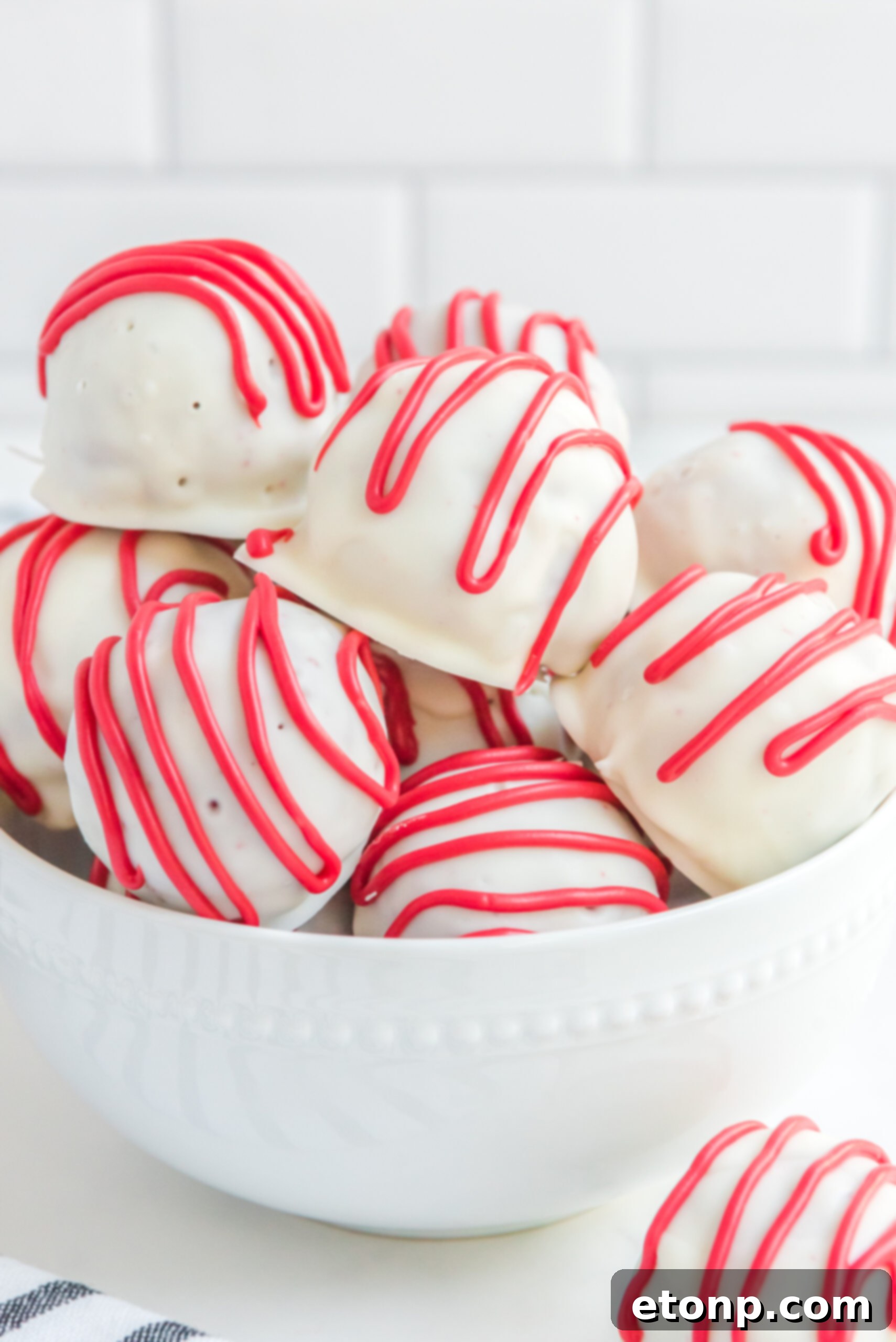 Red velvet cake balls stacked on top of each other in a white bowl.
